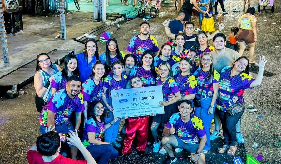 Grupo de participantes posando com um cartão gigante de premiação do Carnararos