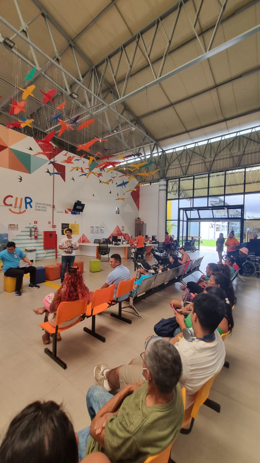 Palestrante falando ao público sentado em frente ao mural colorido do CIIR